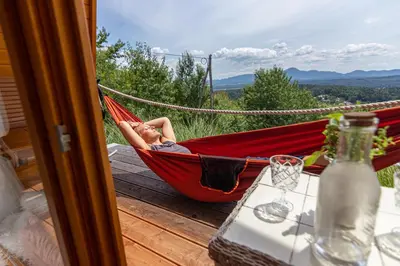 a person sleeping in a hammock on a porch at Panorama Glamping Visole in Slovenska Bistrica