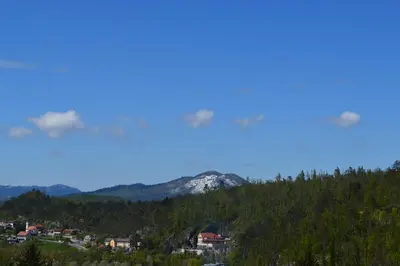 a mountain in the distance with a town and trees at City center blue sky house in Postojna