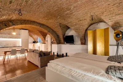 a bedroom with a large bed and a brick wall at Dungeon Apartment in Ljubljana