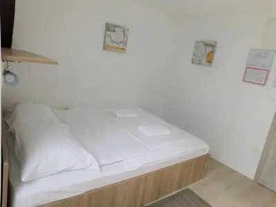 a small bed in a room with white sheets at Evi Rooms Ljubljana in Ljubljana