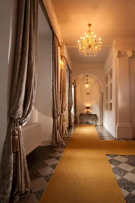 a hallway with a chandelier and curtains and a yellow carpet at Antiq Palace - Historic Hotels of Europe in Ljubljana