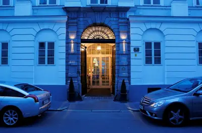 two cars parked in a parking lot in front of a building at Antiq Palace - Historic Hotels of Europe in Ljubljana
