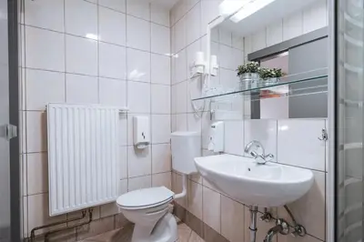 a white bathroom with a toilet and a sink at Pri Karlu Rooms & More in Maribor