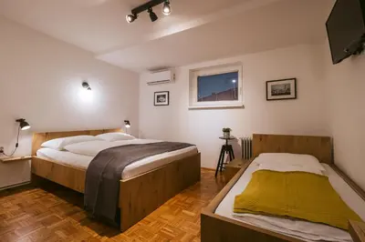 a bedroom with two beds and a flat screen tv at Pri Karlu Rooms & More in Maribor