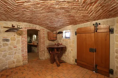 a kitchen with a wooden table in a stone room at Vineyard cottage Zidanca med vinogradi in Otočec