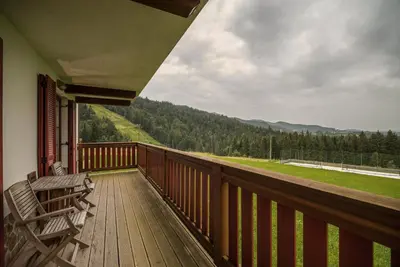a porch with a bench on a deck with a view at Apartmajsko naselje Ribniško Pohorje in Ribnica na Pohorju