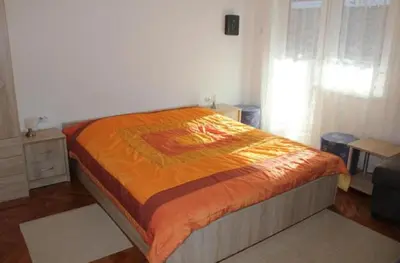 a bed with an orange comforter in a bedroom at Apartments Rozi in Bovec