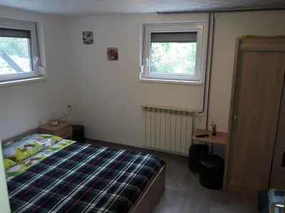 a bedroom with a bed and two windows at Apartments Rozi in Bovec