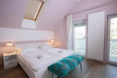 a white bedroom with a bed and a window at Apartments Agenija Bled in Bled