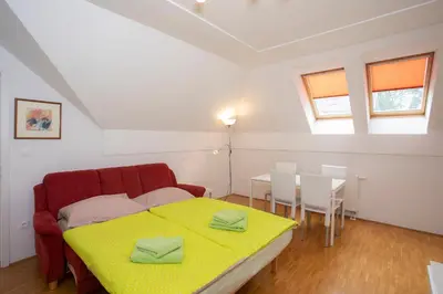 a bedroom with a red couch and a table and chairs at Apartments Agenija Bled in Bled