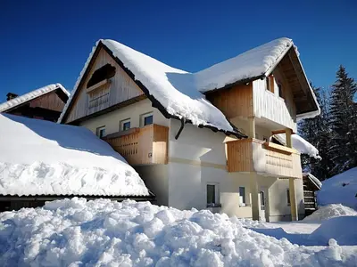 a house covered in snow with a pile of snow at TriSa apartments Bohinj in Bohinj
