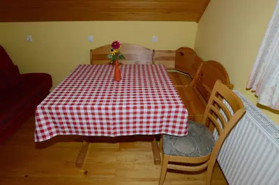a dining room table with a red and white checkered table cloth at Apartment House Koprivnik in Zreče