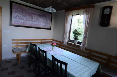 a dining room with a table and chairs and two windows at Apartment House Koprivnik in Zreče