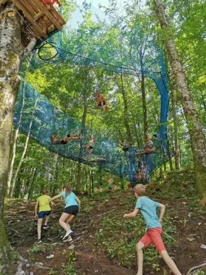 a group of children playing on a climbing net in the woods at Apartma NEVA in Bohinj