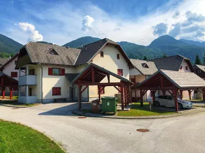 a large house with a car parked in front of it at Apartma NEVA in Bohinj