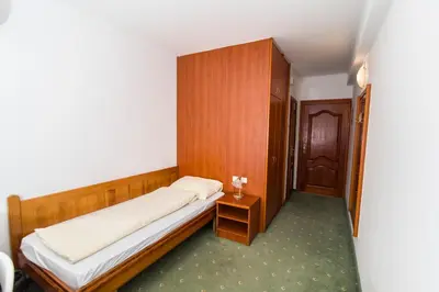 a small bedroom with a bed and a wooden cabinet at Hotel Prebold in Prebold