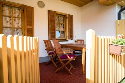 a porch with a wooden table and chairs and a fence at Apartma Marjetica 2 in Moravske Toplice