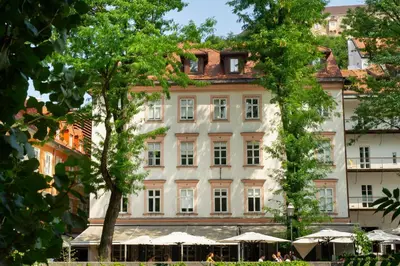a large white building with trees in front of it at Julija&Robert's Riverview Apartments and Rooms in Ljubljana
