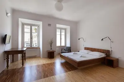 a bedroom with a bed and a desk and a piano at Julija&Robert's Riverview Apartments and Rooms in Ljubljana