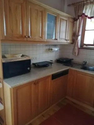 a kitchen with wooden cabinets and a black microwave at Apartment Bolfenk in Pohorje