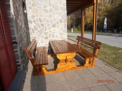 a wooden picnic table and two chairs on a porch at Apartment Bolfenk in Pohorje