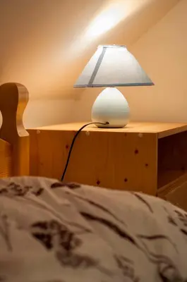 a lamp sitting on a table next to a bed at Apartment Sara in Vitanje