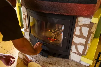 a man is putting something into a fireplace at Apartment Sara in Vitanje