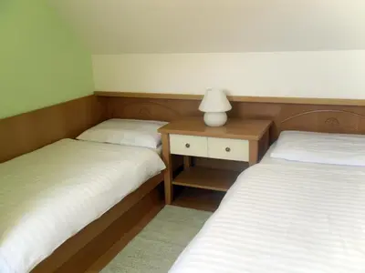 two twin beds in a room with a lamp on a table at Apartmaji Hribar Pr'Ostank in Kamnik