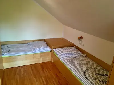 two beds in a small room with wooden floors at J-Max in Bled