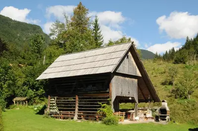 a large wooden barn with a metal roof at Apartmaji Rabič in Bohinj