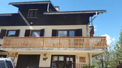 a house with a wooden balcony on top of it at Farm stay Majdač in Solčava