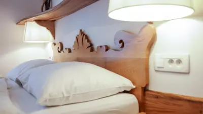 a bedroom with a bed with a wooden headboard and a lamp at Central Bled House in Bled