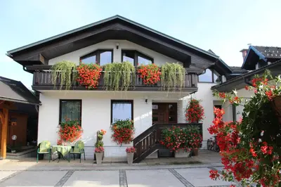 a white house with flowers on the balconies at Garden Apartments Janša in Radovljica