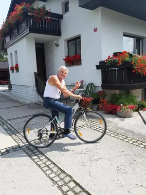 a man riding a bike in front of a house at Garden Apartments Janša in Radovljica