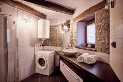 a bathroom with a washing machine and a sink at Tmbin's barn - nature, horses, family in Sežana