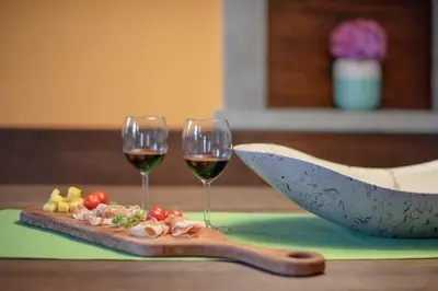 two glasses of wine and a cutting board with food at Tmbin's barn - nature, horses, family in Sežana