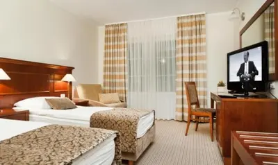 a hotel room with two beds and a flat screen tv at Hotel Cateski Dvorec in Čatež ob Savi