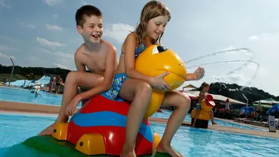 a boy and a girl sitting on top of a raft in a pool at Hotel Cateski Dvorec in Čatež ob Savi