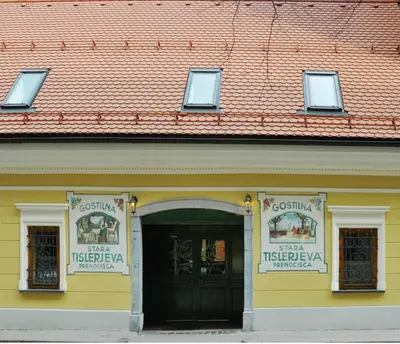 a yellow building with a black door and two windows at Guesthouse Stari Tišler in Ljubljana