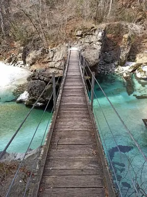 a wooden bridge over a river with blue water at Apartment Nevela in Bovec