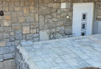 a building with a stone wall and a white door at Čebelja Zibka in Ljubljana