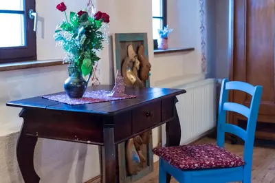 a table with a vase of flowers and a chair at Homestead farm Tešnak in Gorenja Vas