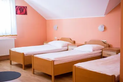 three beds in a room with orange walls at Guesthouse Beno in Starše