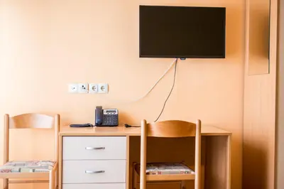 a room with a desk with a phone and a tv at Guesthouse Beno in Starše