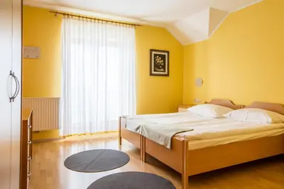 a bedroom with a bed with yellow walls and a window at Guesthouse Beno in Starše