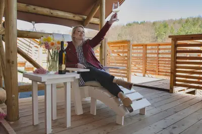 a woman sitting at a table with a glass of wine at Glamping SUN VALLEY Bioterme in Mala Nedelja