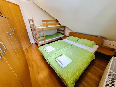 a small bedroom with a green bed and a ladder at Apartma Manca in Kranjska Gora