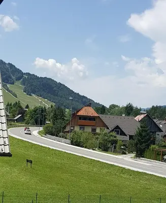 a winding road in a village with houses and a mountain at Apartma Manca in Kranjska Gora