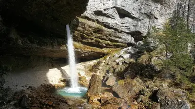 a waterfall on the side of a mountain next to a river at Apartma Manca in Kranjska Gora