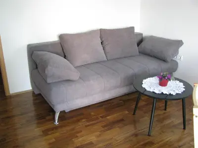 a grey couch in a living room with a table at Hiša marjetica in Maribor